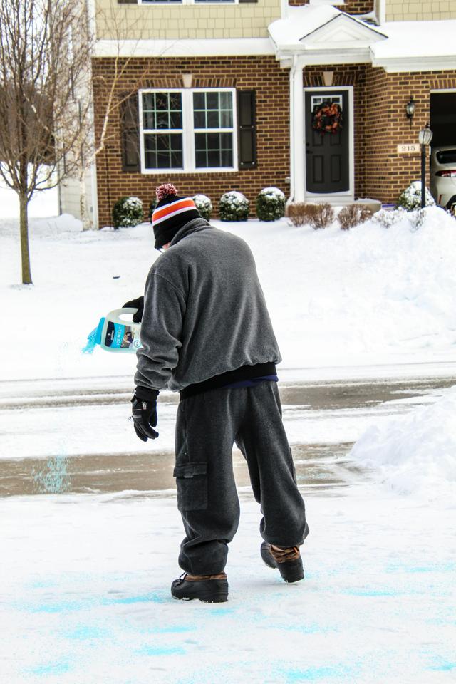 man putting salt on a driveway