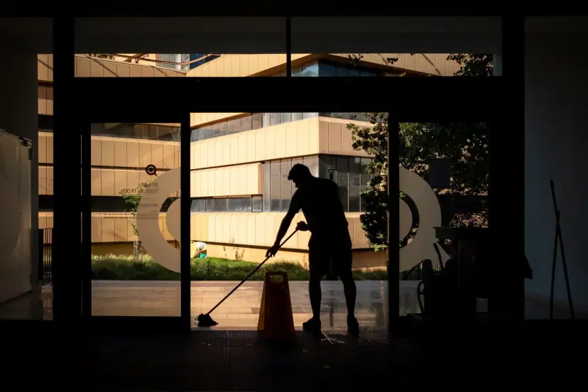 Silhouetted worker sweeping outdoor courtyard