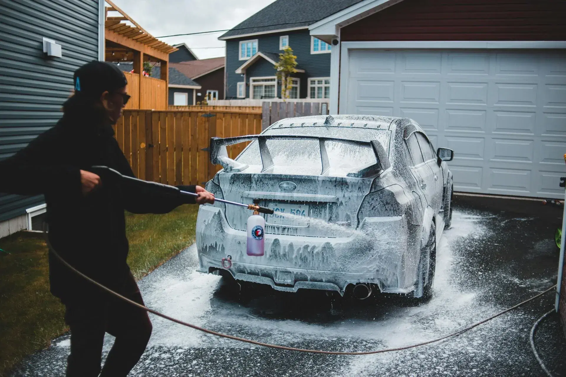 Person washing car with pressure washer