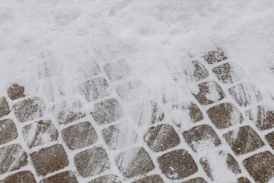 A closeup of geometric paving stones partially covered in winter snow.