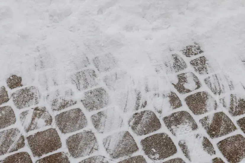 A closeup of geometric paving stones partially covered in winter snow.