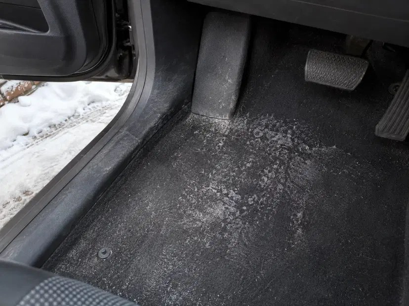 Salt-stained car footwell carpet in an Ottawa driveway with snow outside