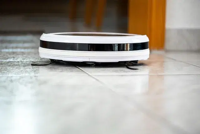 Robot vacuum cleaning a hardwood living room floor near furniture