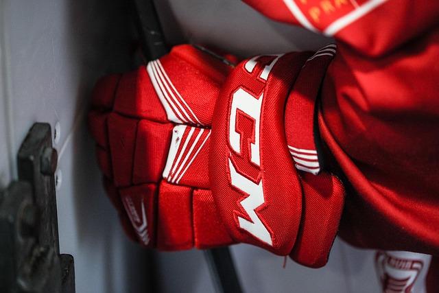 Hockey player wearing gear including gloves and stick on an ice rink